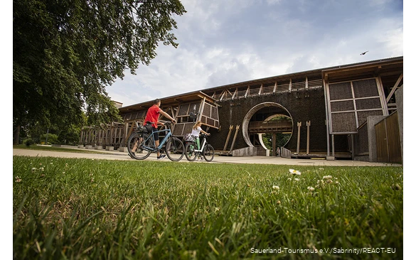 Zwei Radfahrer schieben die Fahrräder vor dem Gradierwerk in Bad Sassendorf