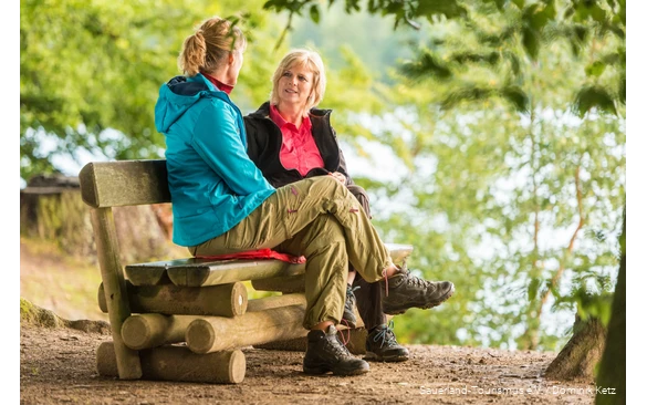 Zwei Frauen sitzen auf einer Bank am Möhnesee und unterhalten sich.
