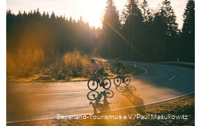 Zwei Rennradfahrer bei Sonnenaufgang auf einer Sepentine