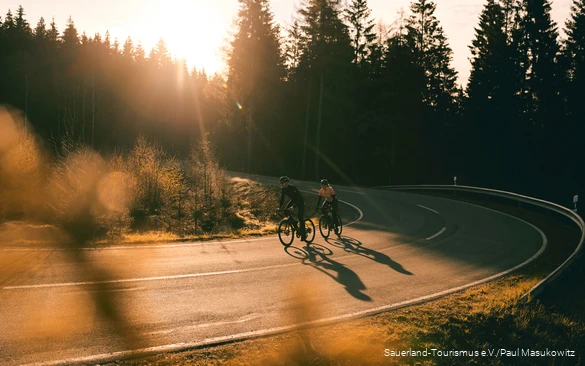 Zwei Rennradfahrer bei Sonnenaufgang auf einer Sepentine