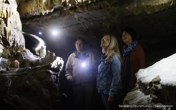 Zwei Frauen und der Höhlenführer bestaunen die Höhle.