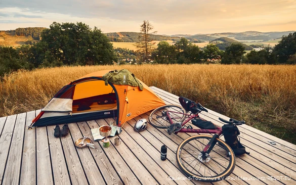 Gravelbike und Zelt auf einer Trekkingplattform mit Blick über die Landschaft des Sauerlandes