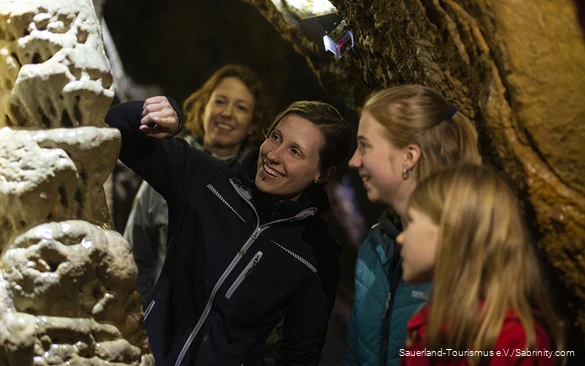 Die Höhlenführerin erklärt zwei Kindern die Tropfsteinhöhle.