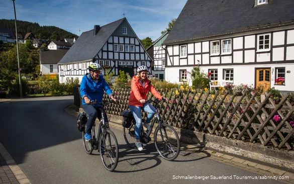 Ein Paar unternimmt eine Radtour durch ein Fachwerkdorf.