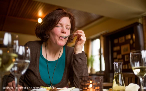 Eine Frau genießt ihr Essen in einem Sauerländer Gasthof.