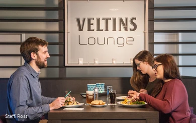 Eine Gruppe isst in der Veltins Lounge des Oversusms in Winterberg.