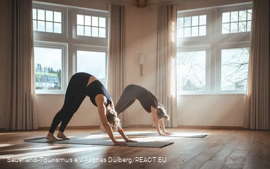 Zwei Frauen machen eine Yogaübungen in einem lichtdurchflutetem Raum