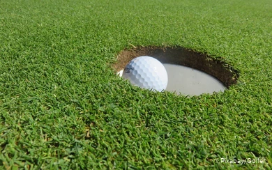 Ein Golfball liegt im Loch.