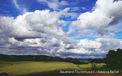 Dicke Wolken am blauen Himmel ziehen über die Sauerländer Landschaft.